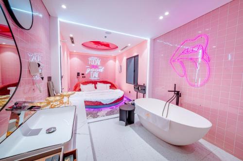 a pink bathroom with a tub and a bed at X-Digital HOTEL in Bắc Ninh