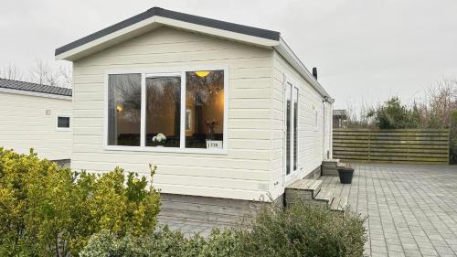 ein kleines weißes Gebäude mit einem Fenster zu einer Terrasse in der Unterkunft J 228 in Petten