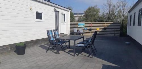 eine Terrasse mit Tisch, Stühlen und einer Bank in der Unterkunft J 228 in Petten