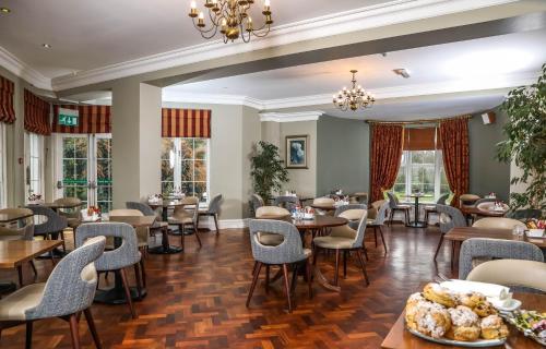 a restaurant with tables and chairs and windows at Springfort Hall Hotel in Mallow