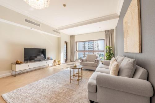 a living room with a couch and a tv at Ultra Luxury Palm - Free 5-star Beach Resorts Access in Dubai