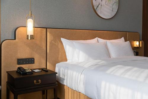 a bedroom with a white bed with a night stand with a clock at Dong Fang Hotel Guangzhou - Free Canton Fair Shuttle Bus & Overseas Buyer Registration Services in Guangzhou