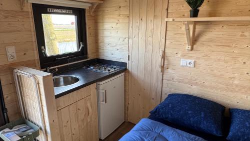 a small kitchen with a sink in a wooden cabin at Kampeerwagon in Petten