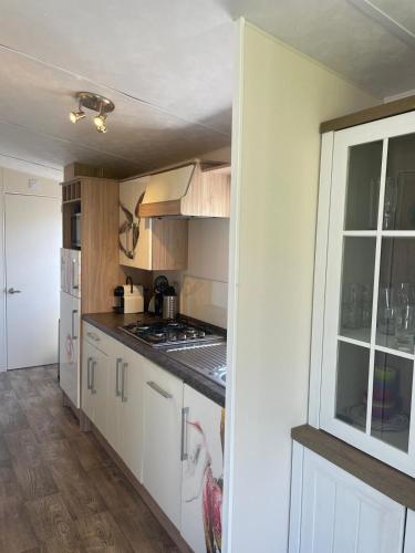 a kitchen with white cabinets and a stove top oven at Chalet 240 in Petten