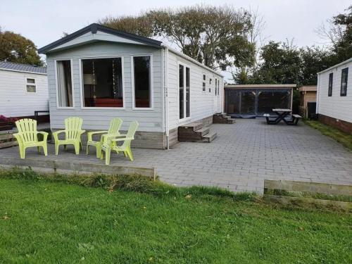 a patio with yellow chairs and a house at Chalet 240 in Petten