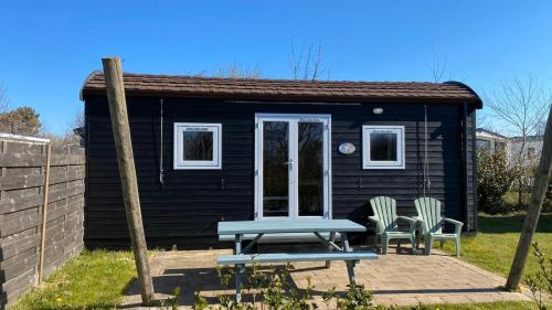 a small black shack with a picnic table and two chairs at Campervan in Petten