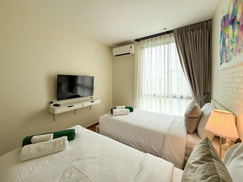 a hotel room with two beds and a flat screen tv at Modern 1 & 2 Bedroom Apartments Naiyang Phuket by Mango Family in Nai Yang Beach