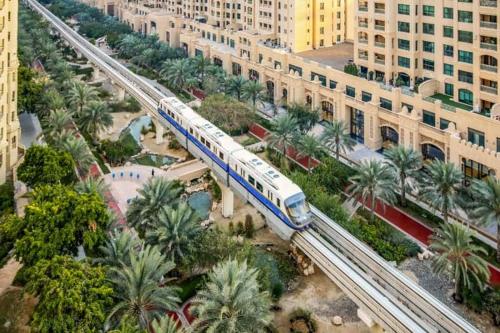 a blue and white train on tracks in a city at Ultra Luxury Palm - Free 5-star Beach Resorts Access in Dubai