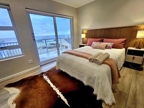 a bedroom with a large bed with a large window at Hysie oppie see in Jongensfontein