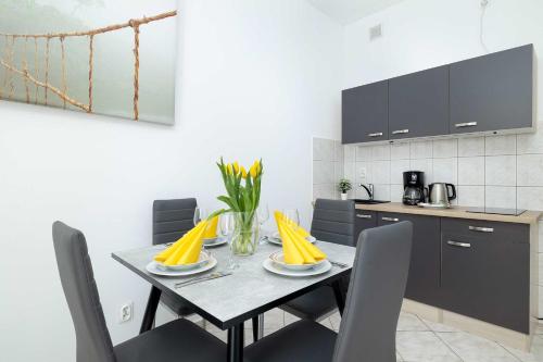 ein Esstisch mit Stühlen und eine Küche in der Unterkunft Comfortable Studio for 3 People with Parking in Kołobrzeg by Noclegi Renters in Radzikowo