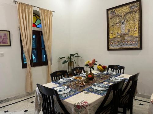 a dining room with a table and chairs with plates and dishes at Shivrati Vilas, Himmat bagh in Udaipur