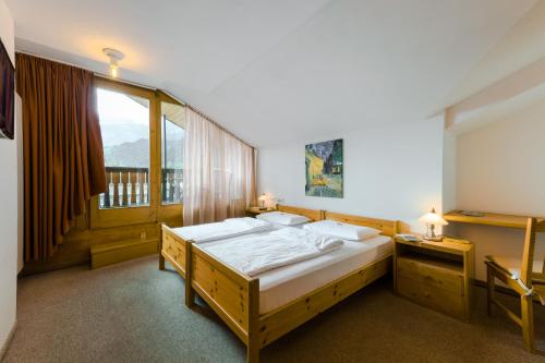 ein Schlafzimmer mit einem großen Bett und einem Fenster in der Unterkunft Hotel Suisse, Swiss Alpine Charm in Poschiavo