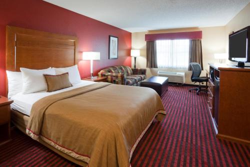 ein Hotelzimmer mit einem Bett und einem TV in der Unterkunft GrandStay Hotel & Suites - Stillwater in Stillwater