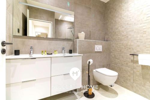 une salle de bain avec toilettes, lavabo et miroir dans l'établissement SELECT'soHOME - Villa avec piscine, spa et babyfoot pour 10 personnes à proximité de la plage d'Aiguebelle ! - 5 ETOILES - VILLA MANDARINIERS, au Lavandou