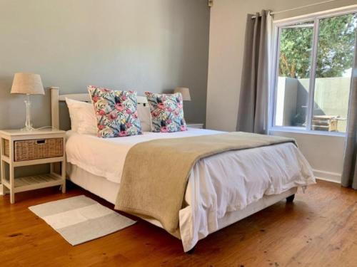 赫曼努斯Hermanus Self-Catering的一间卧室，配有一张床、枕头和一扇窗户