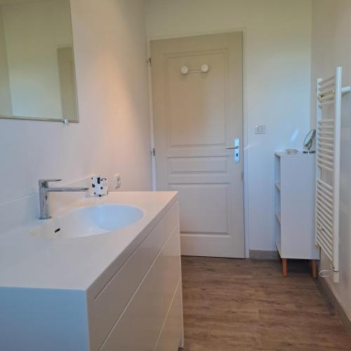 a white bathroom with a sink and a refrigerator at La Garenne in Virazeil