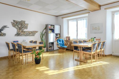 ein Zimmer mit zwei Tischen und Stühlen sowie einem Kühlschrank in der Unterkunft Hotel Suisse, Swiss Alpine Charm in Poschiavo