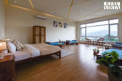a bedroom with a large bed and a living room at StayVista at Anandam Lake Villa - Khadakwasla in Pune