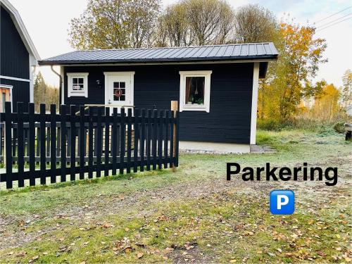 a black house with a fence in front of it at Stugan Karmaleily in Gävle