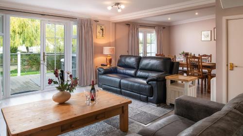 a living room with a leather couch and a table at Venture Lakeside Lodge in South Cerney