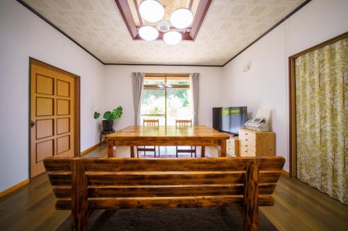 a dining room with a wooden table and a bench at お宿竹あかりOyado Takeakari in Takachiho