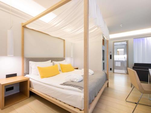 ein Schlafzimmer mit einem Himmelbett und gelben Kissen in der Unterkunft ibis Styles Tallinn in Tallinn