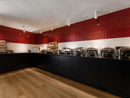 Un restaurante con un mostrador con sillas contra una pared roja. en ibis Styles Tallinn, en Tallin