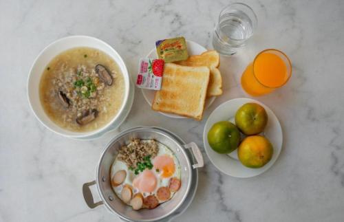 Una mesa con cuencos de comida y un tazón de sopa y tostadas. en R2 Bed and Pool Kanchanaburi, en Kanchanaburi
