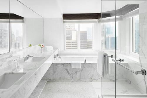 a white bathroom with two sinks and a bath tub at The Luxury Collection Hotel Manhattan Midtown in New York