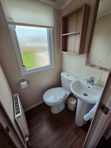 a bathroom with a toilet and a sink and a window at Holiday Home at Hoburne Naish in Barton on Sea