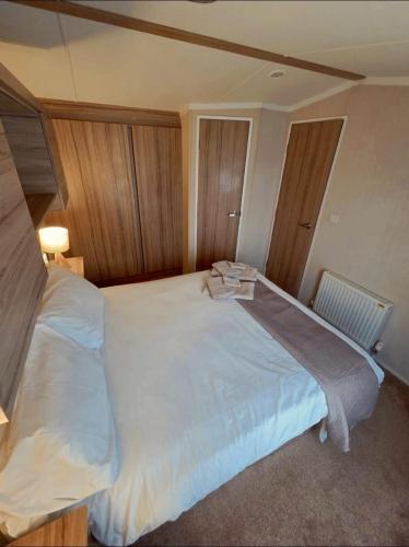 a bedroom with a large bed with white sheets at Holiday Home at Hoburne Naish in Barton on Sea