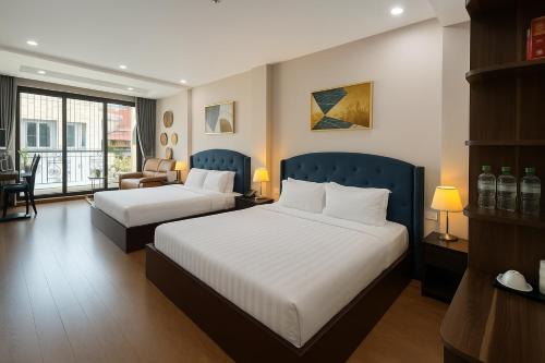 a hotel room with two beds and a chair at Splendid Star Boutique Hotel in Hanoi