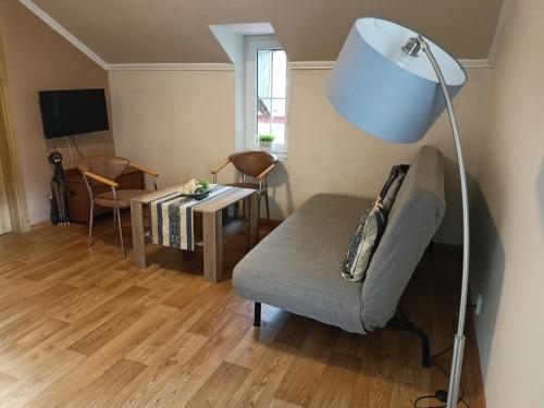 Una sala de estar con una lámpara, un sofá y una mesa. en Penzion Villa Marion, en Mariánské Lázně