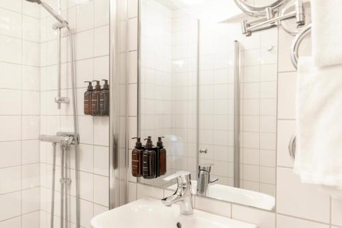 a bathroom with a sink and a shower with bottles at Home Hotel Tapto in Stockholm