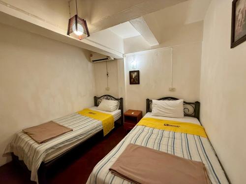 two beds in a small room with yellow and white at Dengba Hostel - Loikroh Chiangmai in Ban Hua Phrong