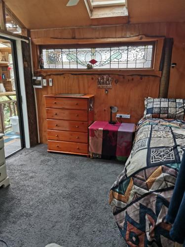a bedroom with a bed and a dresser and a window at The Abel Tasman Treehouse in Marahau