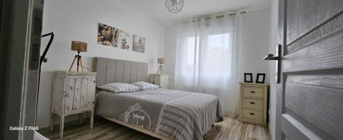 ein Schlafzimmer mit einem Bett, einer Kommode und einem Fenster in der Unterkunft Comme à la maison in Corneville-sur-Risle