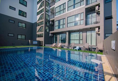 a swimming pool in front of a building at Suntria Hotel Pattaya in Na Jomtien