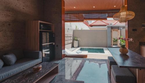 Una sala de estar con un sofá y una piscina. en Dikubu Belong, en Seminyak