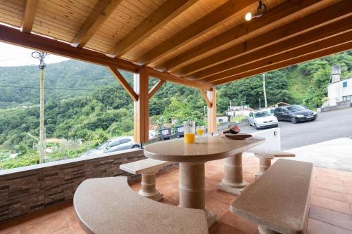 a table and chairs on a patio with a view of a road at Casa Vale Sereno by Rent-a-key in Cabo da Ribeira