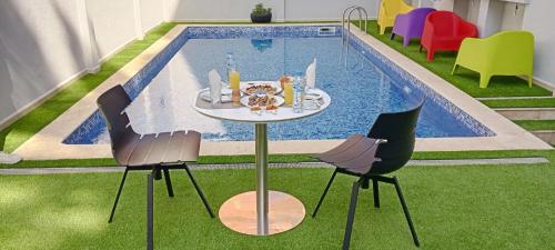 une table et des chaises devant une piscine dans l'établissement Résidence touristique marcadal by Mon rêve, à Fort-de-l'Eau