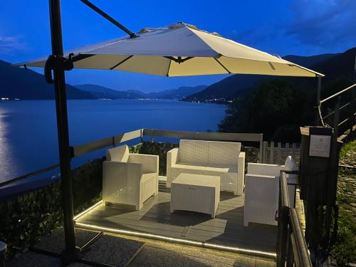 an umbrella and chairs on a deck next to a lake at Rooftop Cannobio in San Bartolomeo