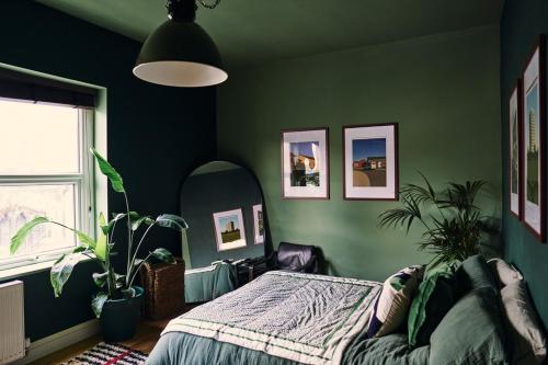 a bedroom with green walls and a bed and a mirror at Mid-Century charm in the heart of Stroud in Stroud
