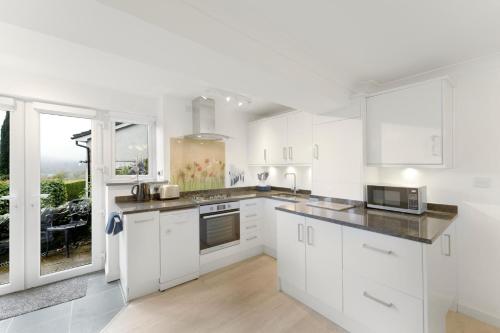 a kitchen with white cabinets and a large window at Fisherbeck Nest in Ambleside