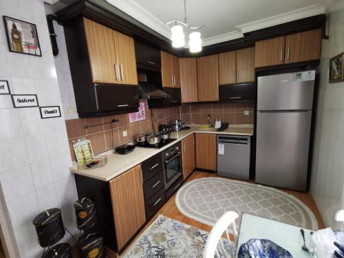 a kitchen with wooden cabinets and a stainless steel refrigerator at 2Ege Üniversitesi ve hastanesine çok yakın Aileye ve Firmaya uygun in Burunabat