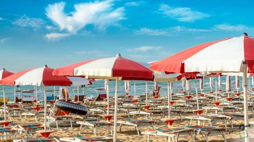 Un montón de sillas y sombrillas en una playa en Hotiday Cecina Mare, en Cecina