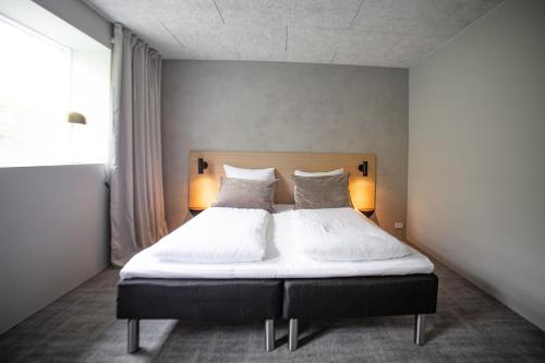 a bedroom with a bed with white sheets and pillows at Hotel Djurhuus in Tórshavn