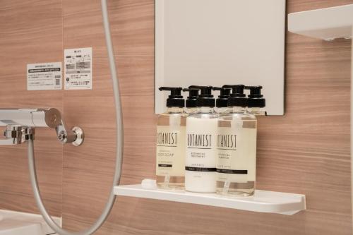 een badkamer met vier flessen toiletartikelen op een plank bij Terrace Tokyo Otsuka in Tokyo
