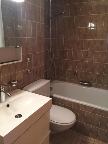 a bathroom with a toilet and a tub and a sink at Roc d'Orsay E51 in Leysin