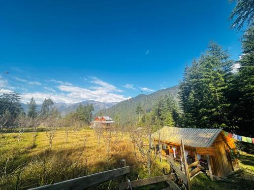 a cabin in a field with mountains in the background at Kath Kuni Cafe & Stay Shangarh in Shangarh